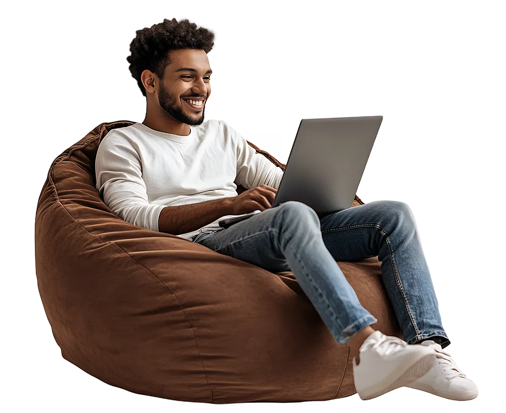 Smiling man on bean bag using laptop, representing a relaxed forex trader.