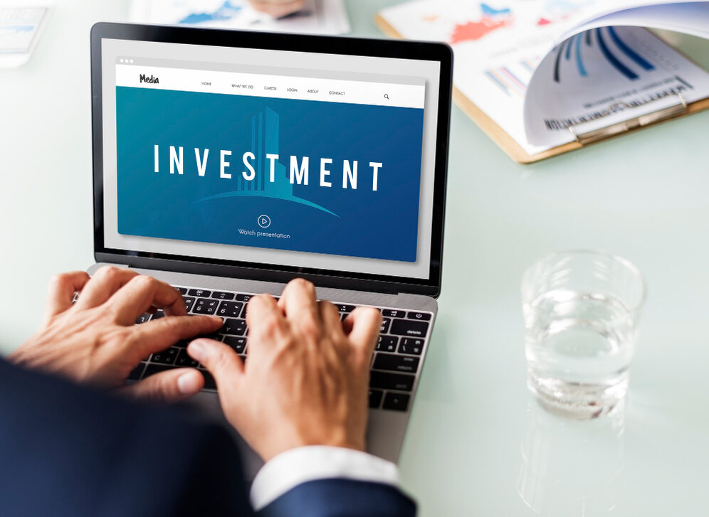 A person working on a laptop displaying the word “Investment” on the screen, symbolizing financial planning and growth, representing Investment Opportunities for NRIs in India.