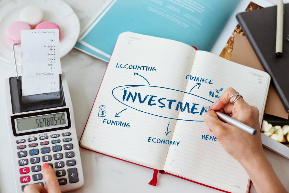 Notebook with the word investment written and financial tools around it, representing common mistakes to avoid when investing and planning a disciplined investment strategy.